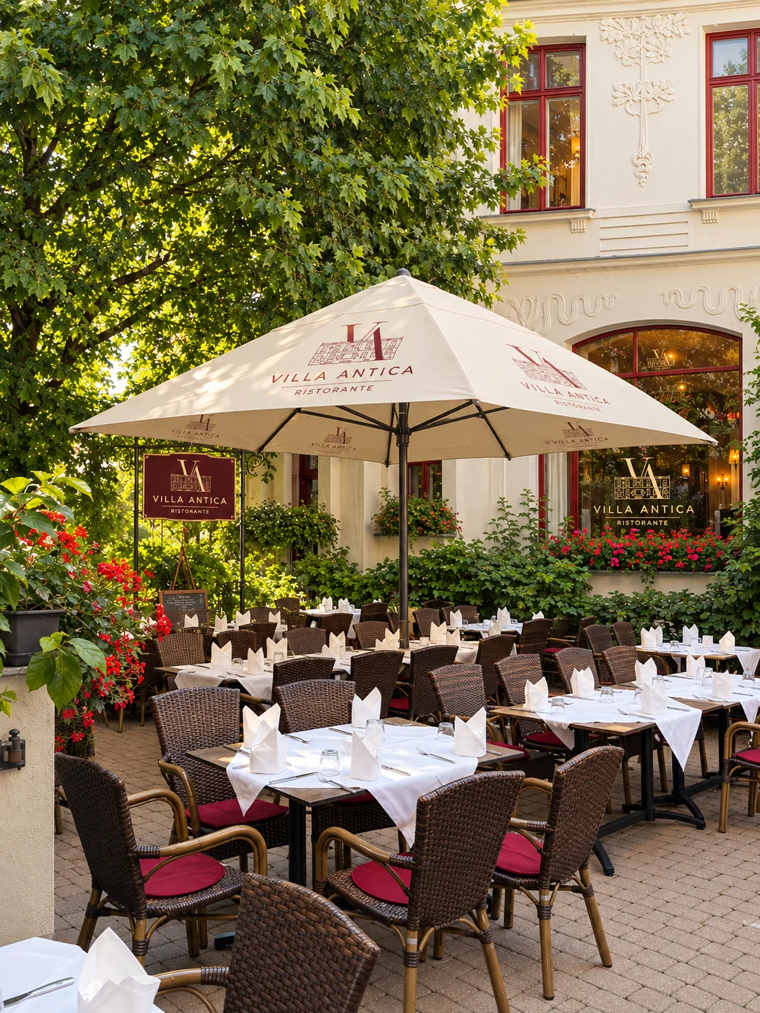 Die grüne Terrasse der Villa Antica mit Sonnenschirm und weißen Tischdecken